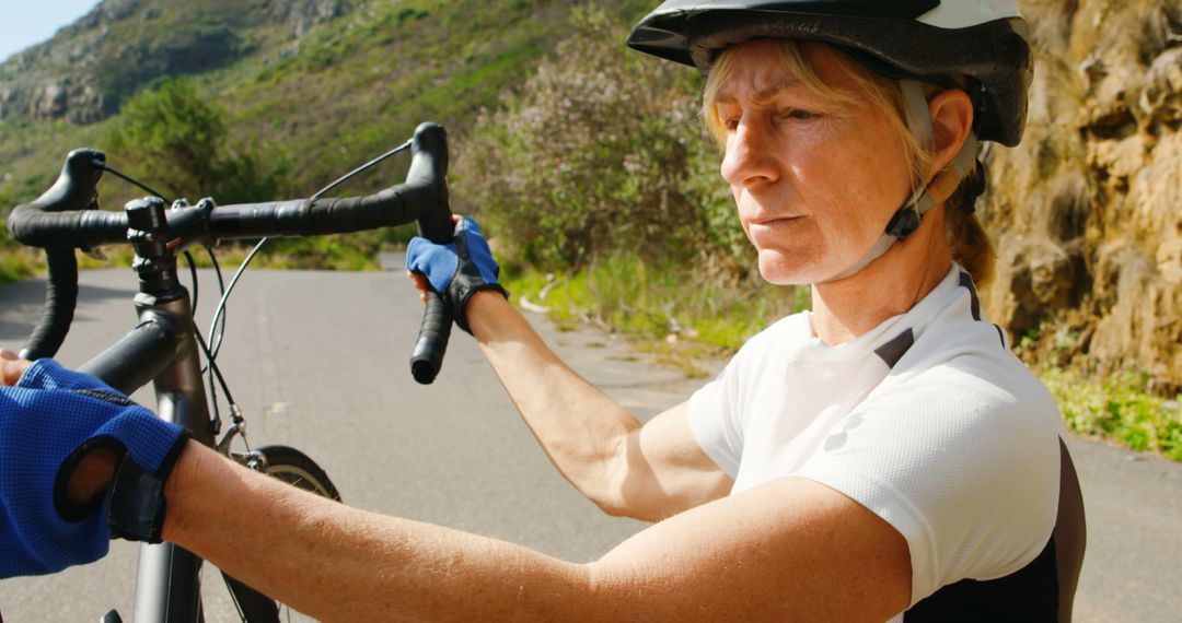 Senior Female Cyclist Adjusting Bicycle on Rural Road - Free Images, Stock Photos and Pictures on Pikwizard.com