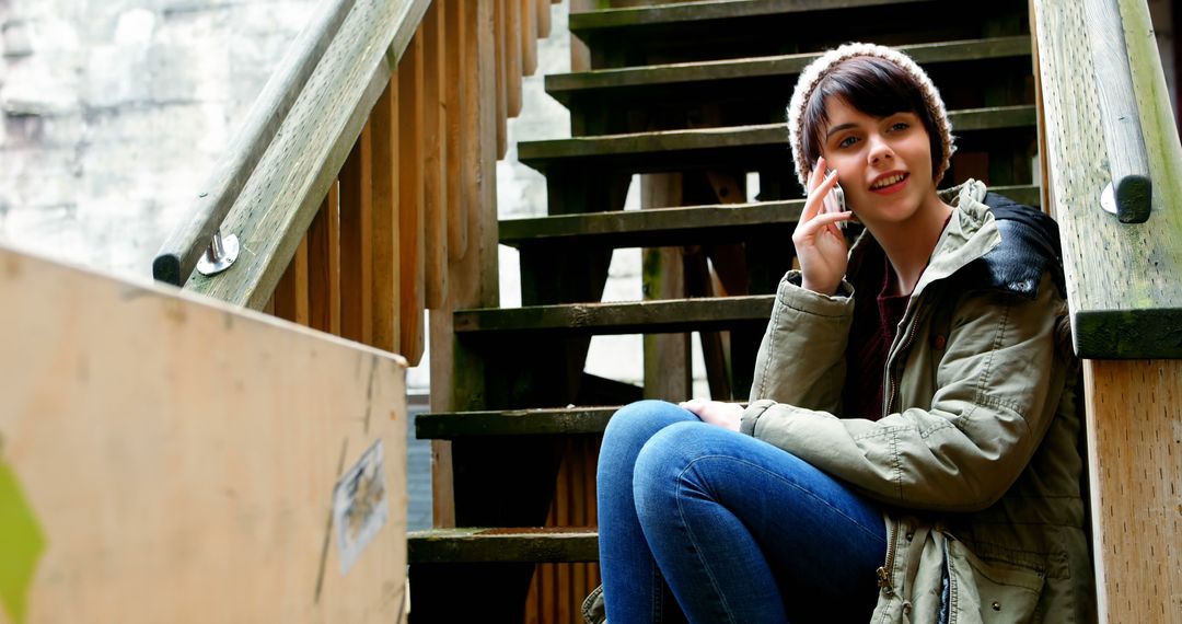 Young Woman Talking on Smartphone Outdoors on Wooden Stairs - Free Images, Stock Photos and Pictures on Pikwizard.com