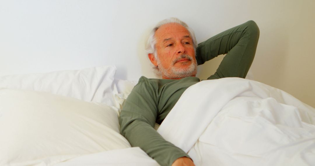 Elderly Man Relaxing in Bed with Thoughtful Expression - Free Images, Stock Photos and Pictures on Pikwizard.com