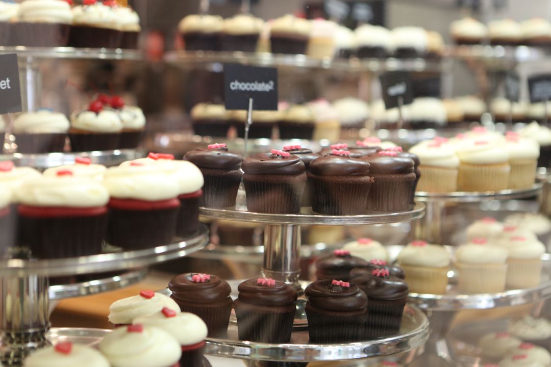 Assorted Cupcakes Display on Glass Shelves in Bakery