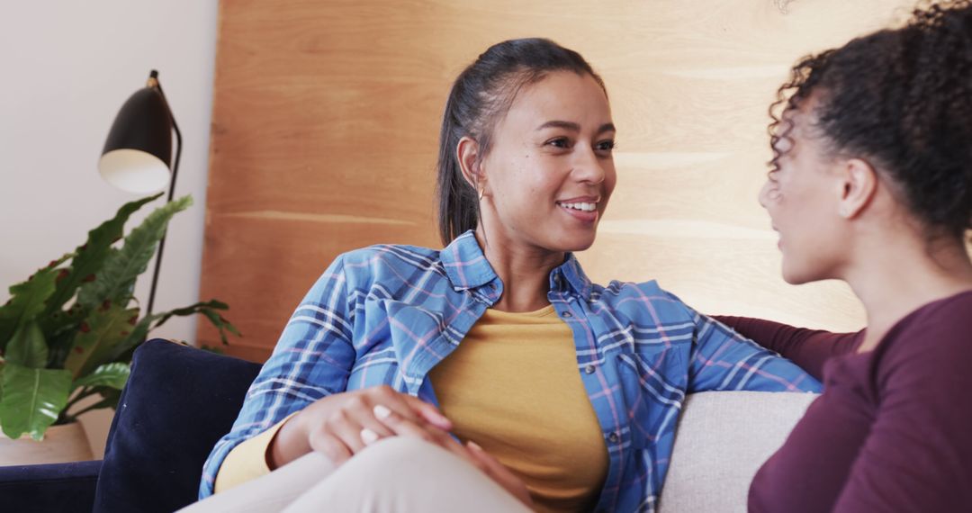 Two Multiethnic Women Relaxing on Couch Engaging in Friendly Conversation - Free Images, Stock Photos and Pictures on Pikwizard.com