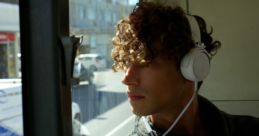 Young Man with Curly Hair Listening to Music on Tram - Free Images, Stock Photos and Pictures on Pikwizard.com