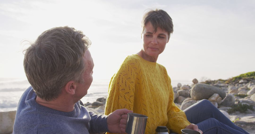 Senior Couple Relaxing at Beach with Coffee at Sunset