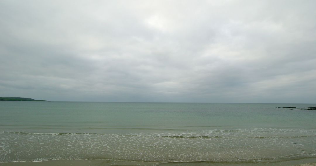 Calm Ocean with Overcast Sky on Tranquil Beach - Free Images, Stock Photos and Pictures on Pikwizard.com