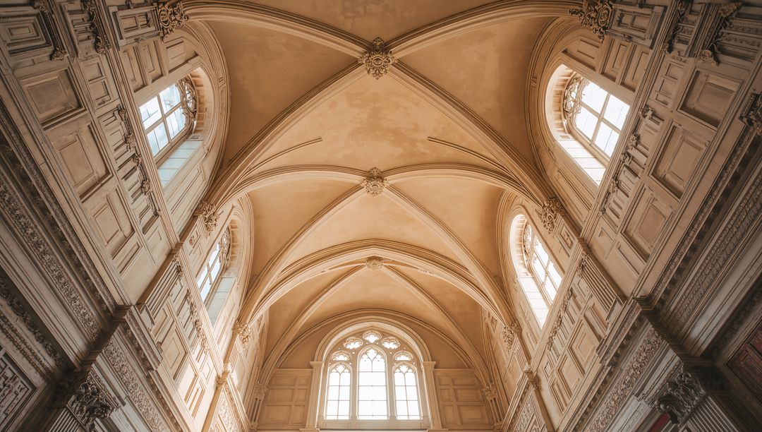 Sunlit Gothic vaulted ceiling in historic chapel with ribbed arches and tracery windows
