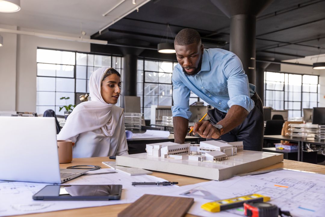 Diverse Coworkers Collaborating Over Architectural Project Model in Office