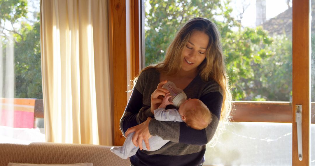 Young Mother Feeding Baby with Bottle in Sunlit Room - Free Images, Stock Photos and Pictures on Pikwizard.com