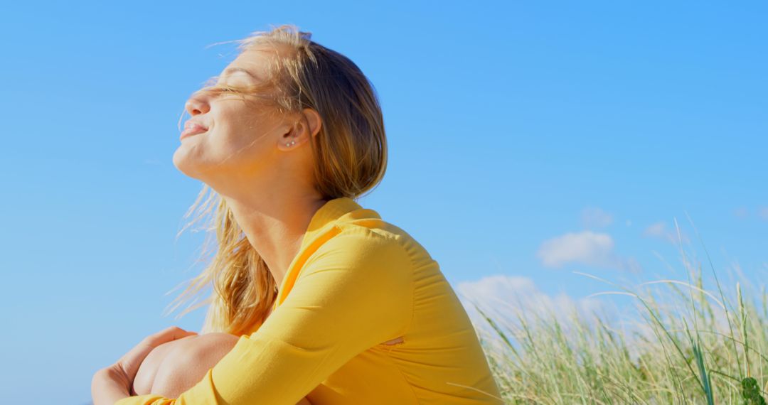 Woman Enjoying Sunlight on Breezy Beach Day - Free Images, Stock Photos and Pictures on Pikwizard.com