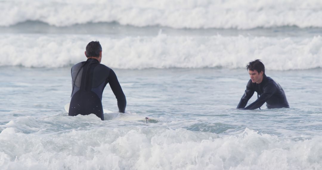 Two Surfers in Wetsuits Waiting for Waves in Ocean Surf - Free Images, Stock Photos and Pictures on Pikwizard.com