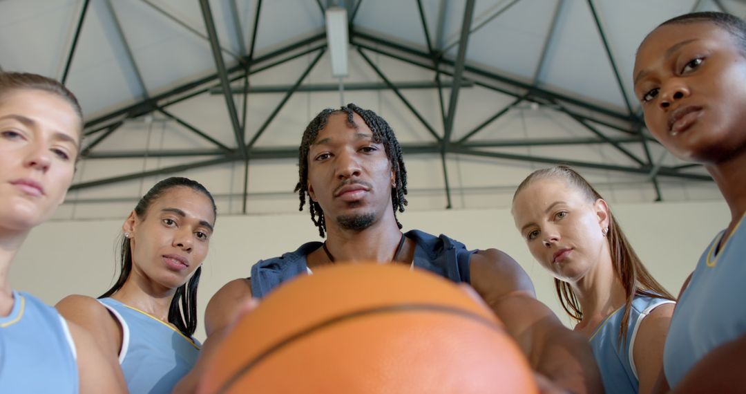 Diverse Basketball Team Huddling with Ball in Gymnasium