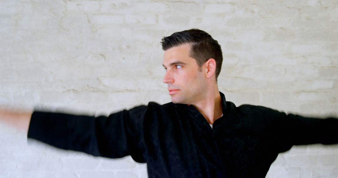 Caucasian man poses in a black shirt against a white wall - Free Images, Stock Photos and Pictures on Pikwizard.com
