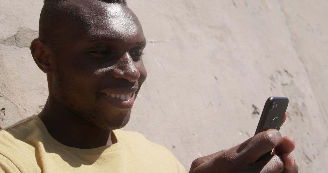Smiling Man Texting at Beach with Smartphone