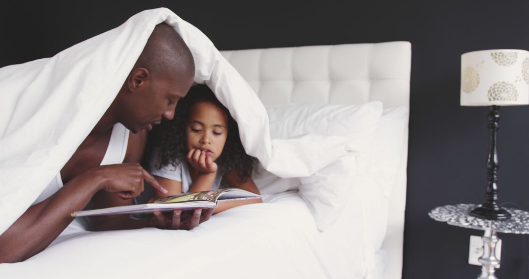 Father and Daughter Reading a Storybook in Bed - Free Images, Stock Photos and Pictures on Pikwizard.com