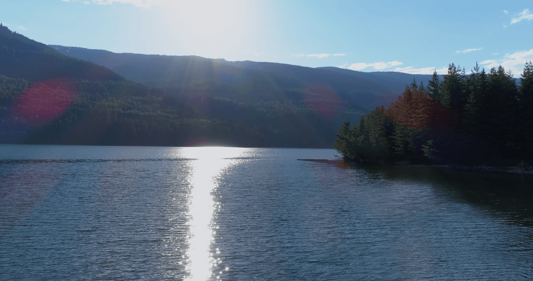 Transparent Sunlight Reflections on Calm River Near Mountains