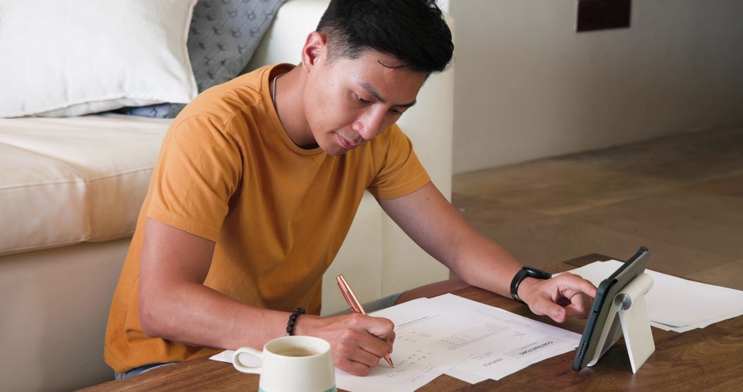 Focused Man Working at Home with Documents and Tablet