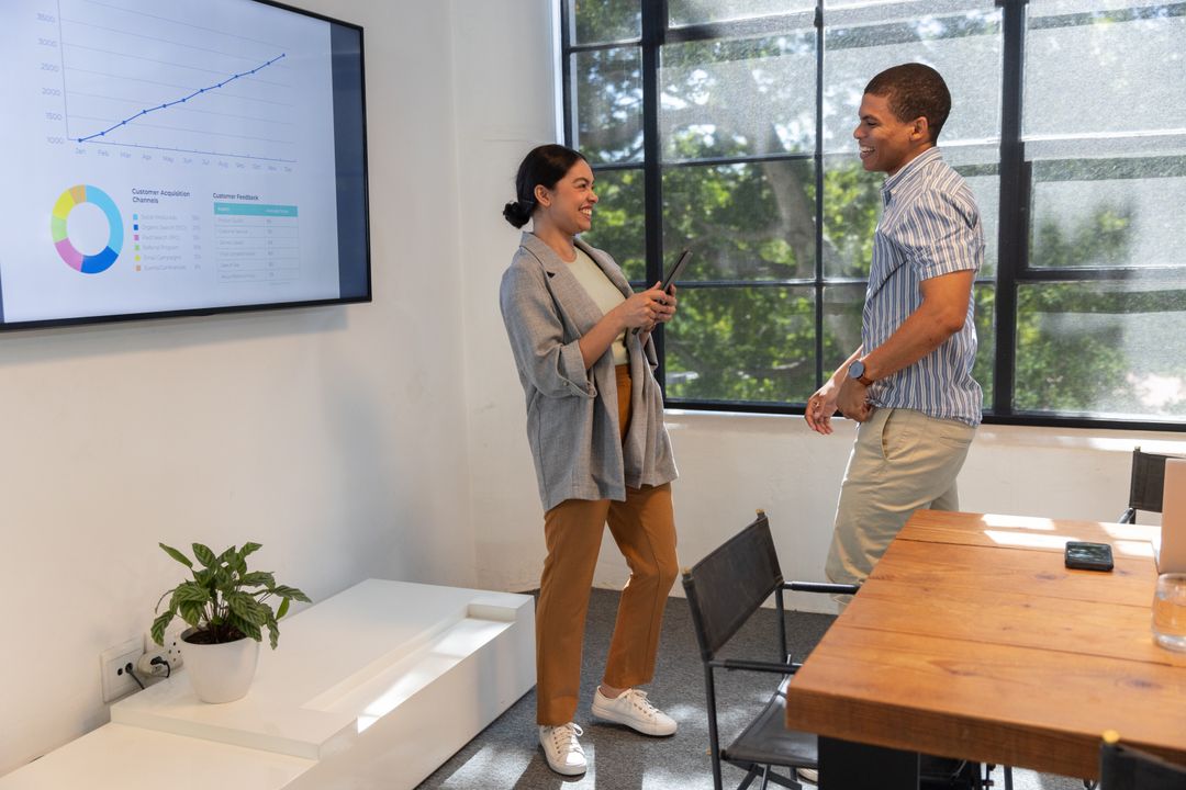 Diverse Coworkers Discussing Data Next to Display in Modern Office