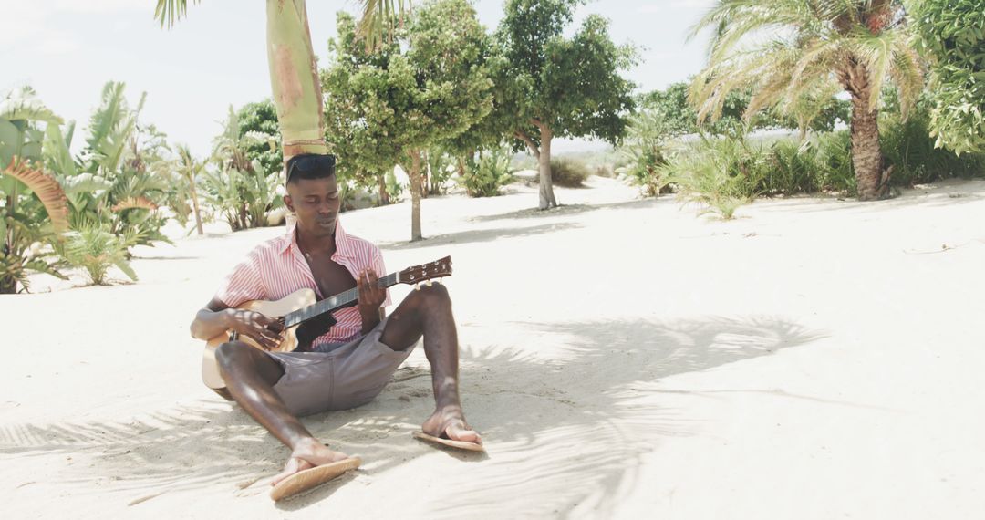 Relaxed Young Man Playing Guitar on a Sunny Beach - Free Images, Stock Photos and Pictures on Pikwizard.com