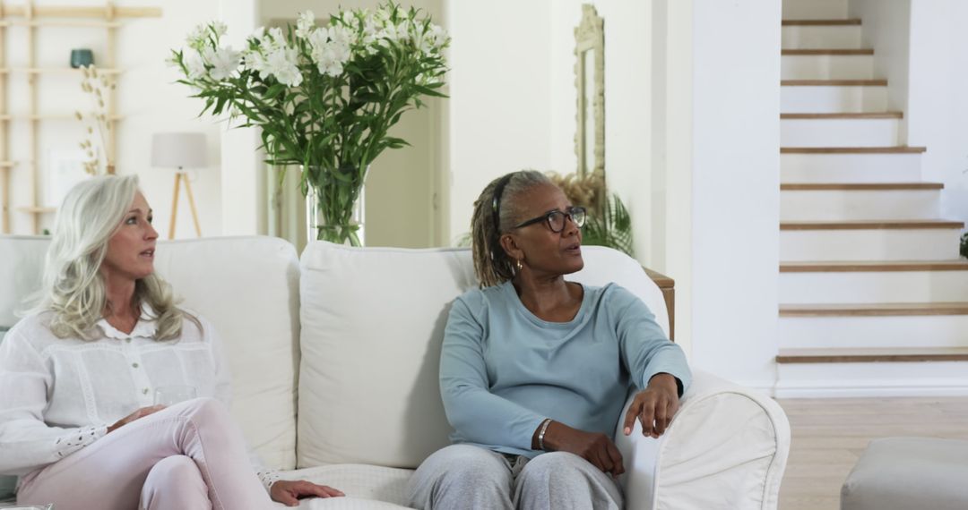 Senior Friends Relaxing on Sofa Having Conversation at Home