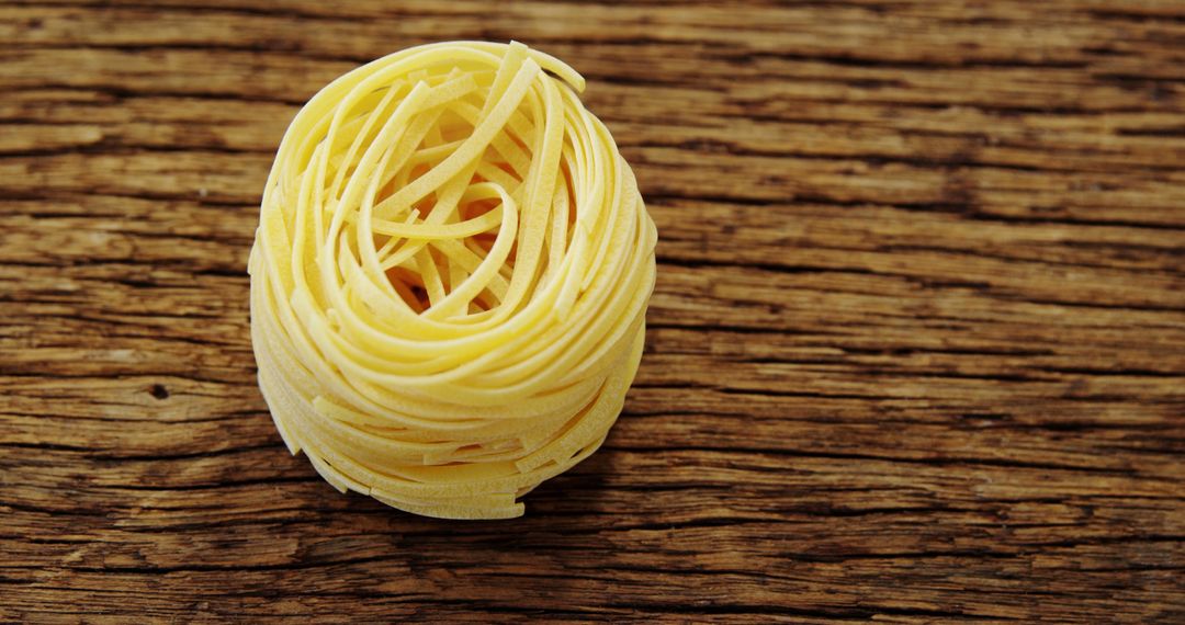 Raw Tagliatelle Pasta Nest on Rustic Wooden Background - Free Images, Stock Photos and Pictures on Pikwizard.com