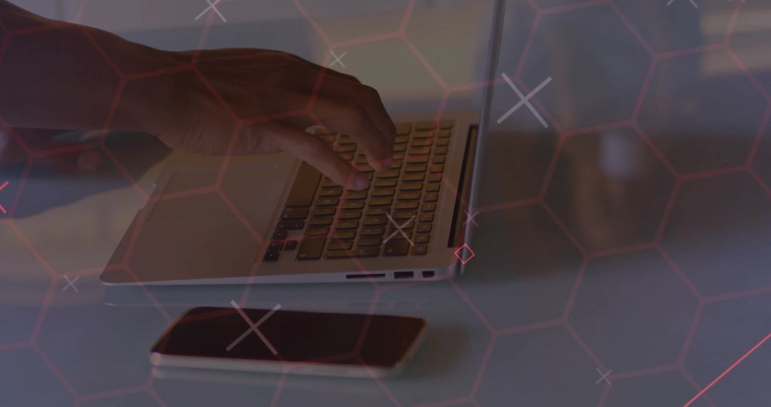 Close-up of Hand Typing on Laptop with Red Hexagonal Grid Overlay