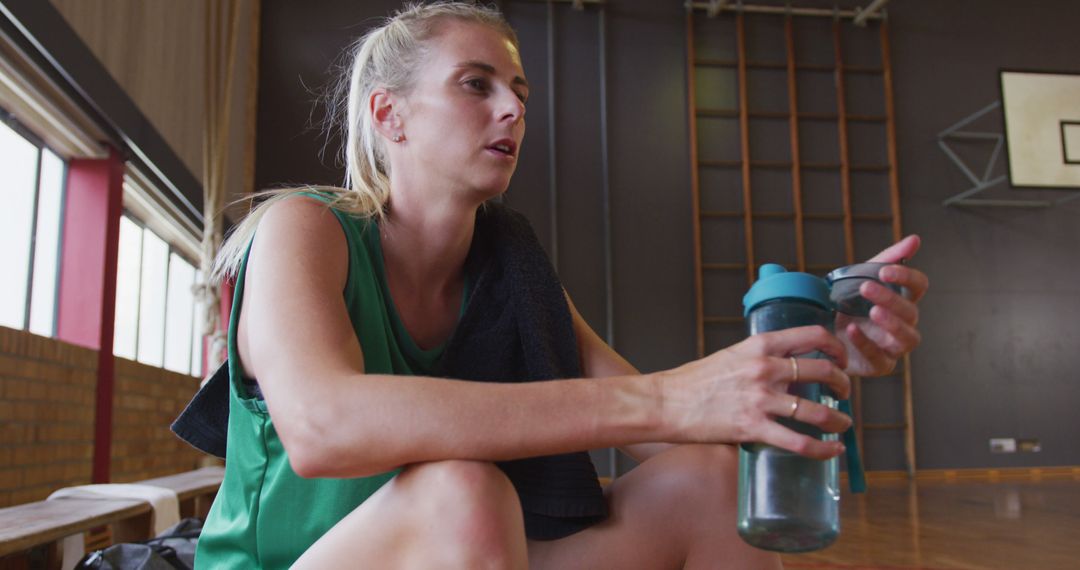 Female Basketball Player Resting and Drinking Water on Court - Free Images, Stock Photos and Pictures on Pikwizard.com