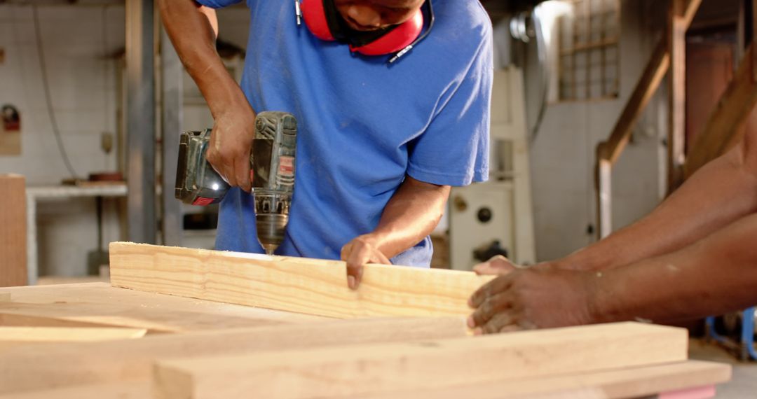 Woodworkers Drilling Plank in Professional Workshop