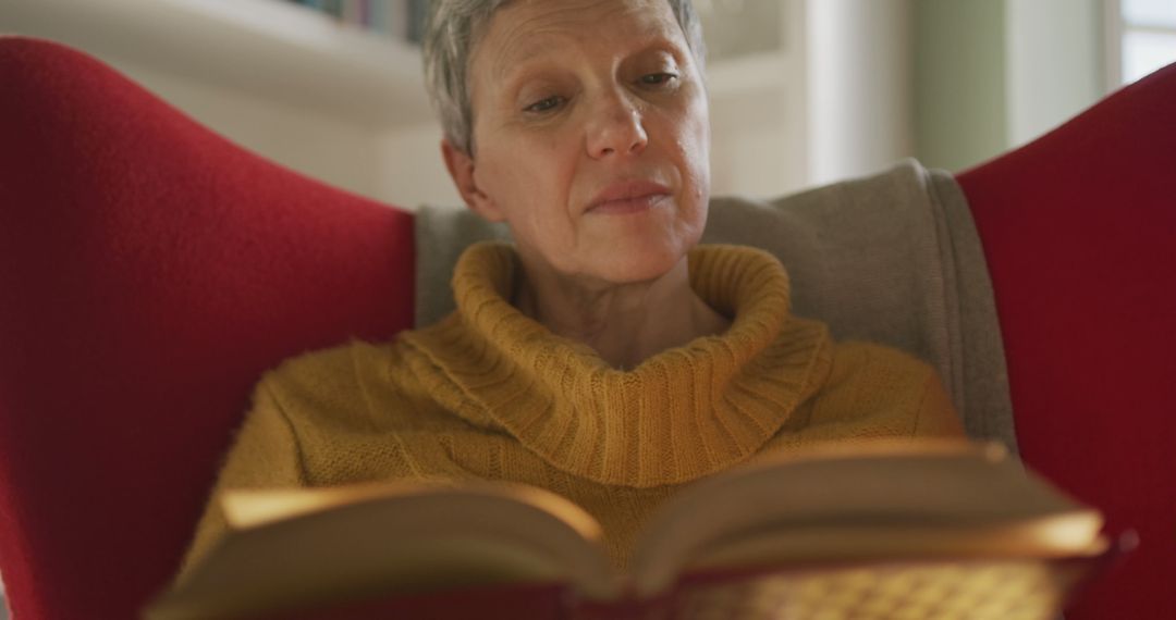 Mature Woman Enjoying Book in Comfortable Red Armchair at Home - Free Images, Stock Photos and Pictures on Pikwizard.com