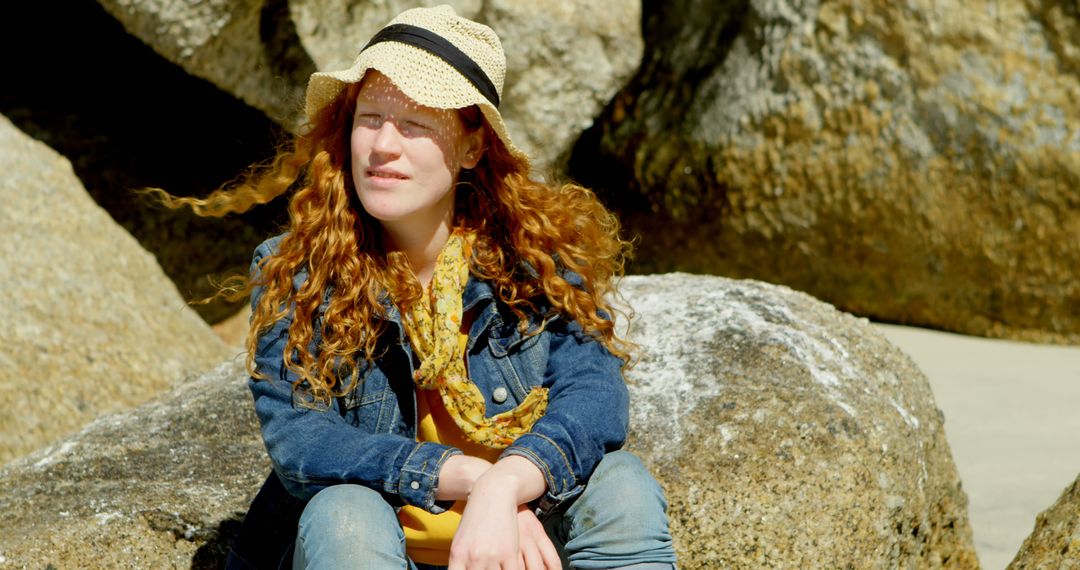 Woman with Straw Hat Enjoying Sunlight Sitting on Rock - Free Images, Stock Photos and Pictures on Pikwizard.com