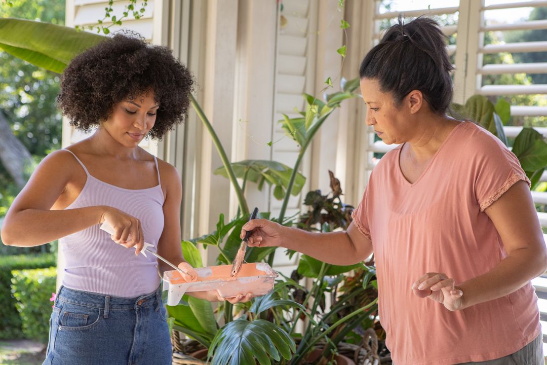 Mother and Daughter Mixing Paint on Porch with Greenery