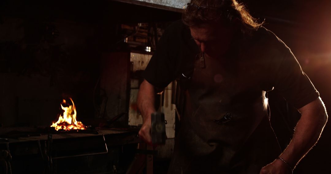 Blacksmith Shaping Metal with Hammer, Workshop Background Enigmatic Lighting - Free Images, Stock Photos and Pictures on Pikwizard.com