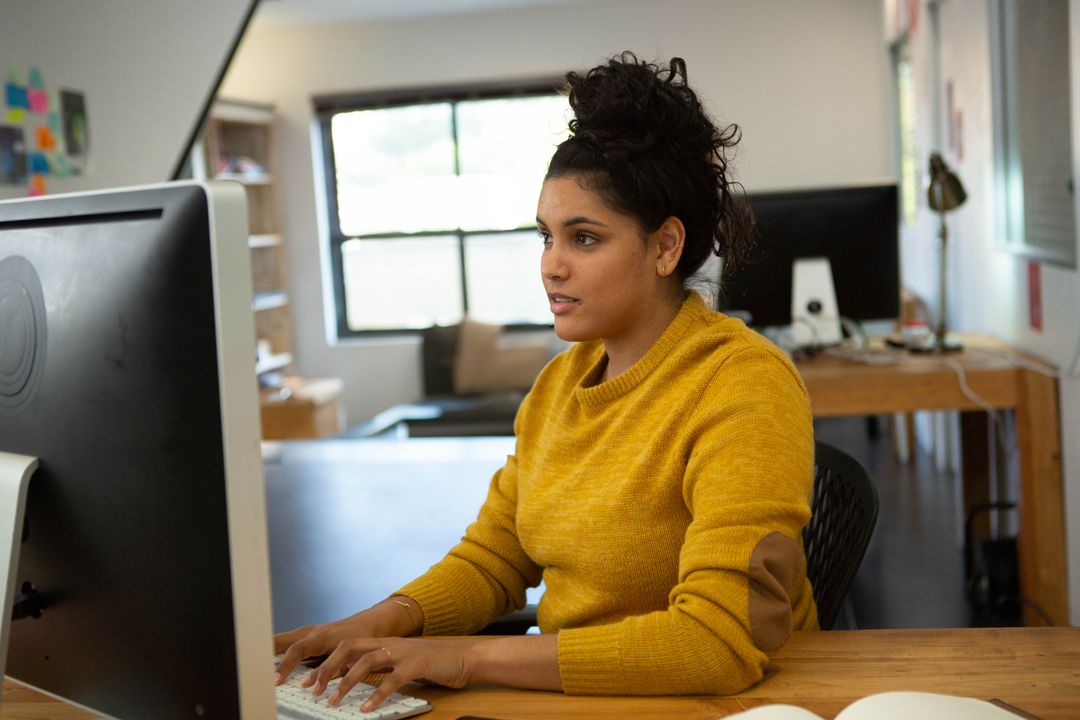 Focused Woman Using Dual Monitors at Modern Office Desk