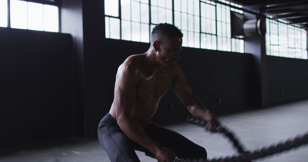 Shirtless african american man exercising battling ropes in an empty urban building - Free Images, Stock Photos and Pictures on Pikwizard.com