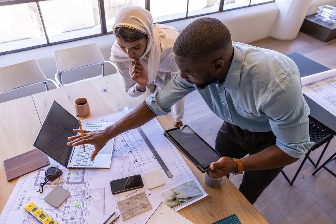 Diverse Team Collaborating on Architectural Blueprint at Bright Workspace