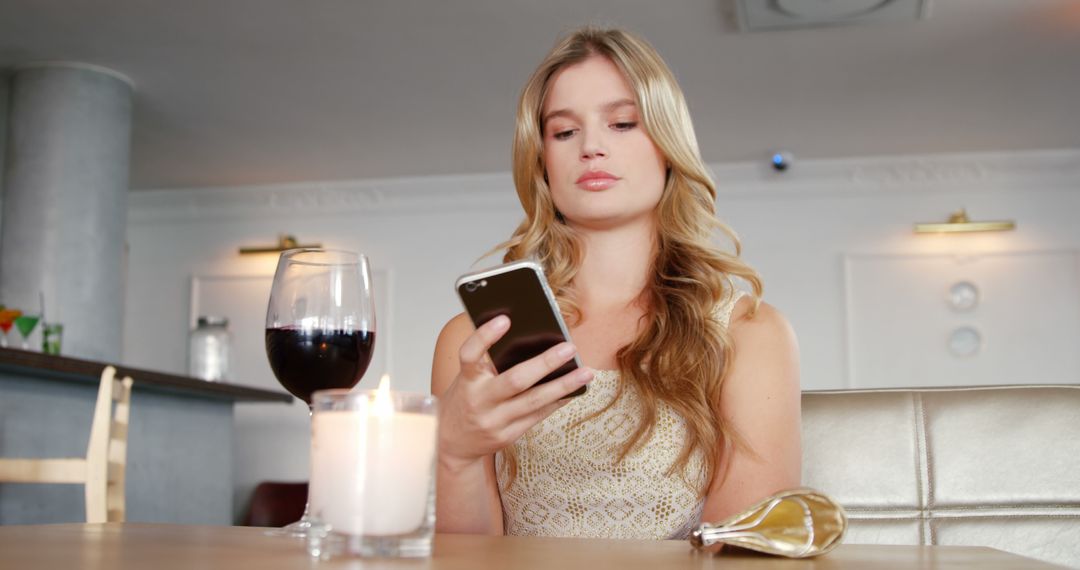 Young Woman Texting on Smartphone at Cafe with Wine and Candle - Free Images, Stock Photos and Pictures on Pikwizard.com