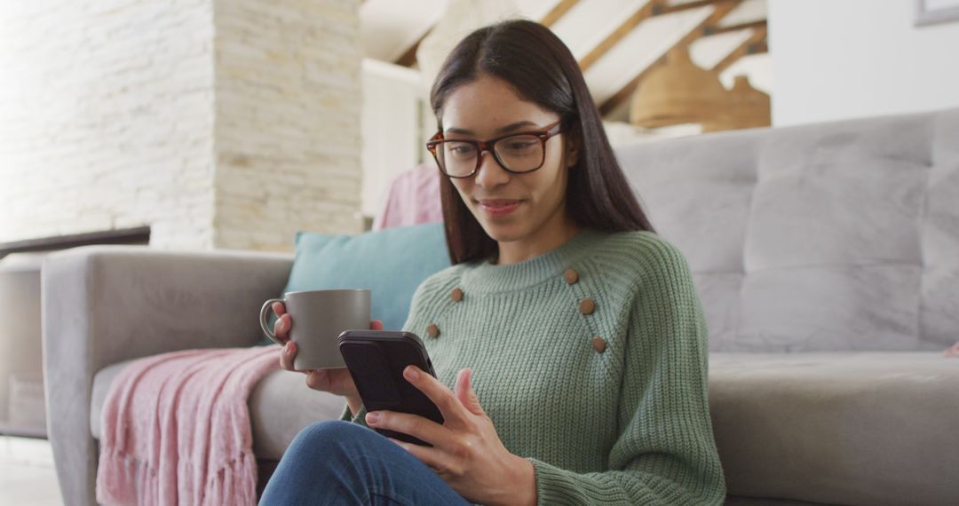 Biracial woman using smartphone and smiling in living room - Free Images, Stock Photos and Pictures on Pikwizard.com