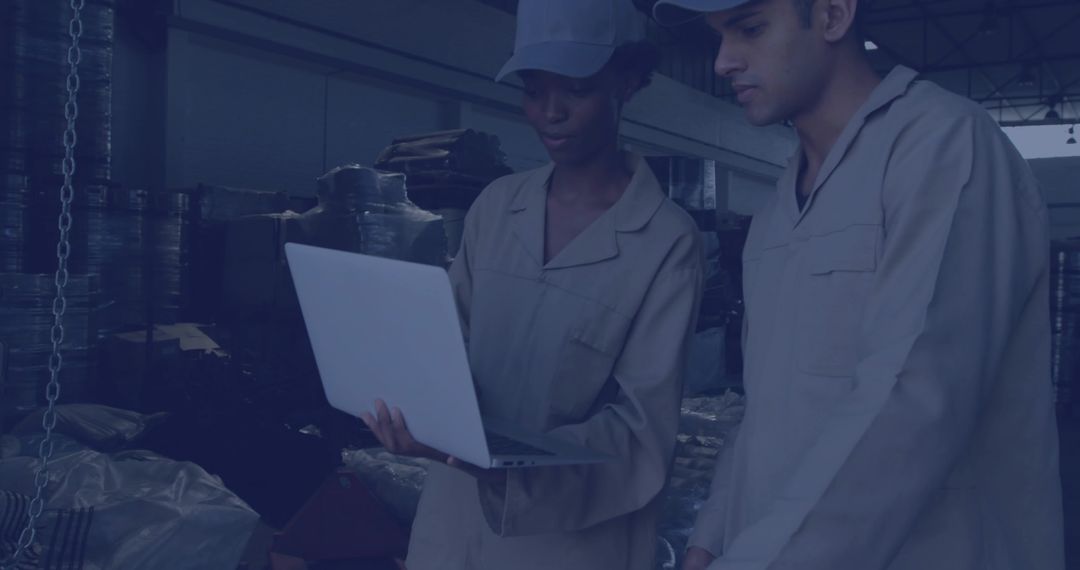 Warehouse Technicians Collaborating on Laptop in Industrial Setting
