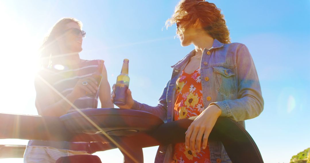 Two Women Enjoying a Sunny Day with Drinks Outdoors - Free Images, Stock Photos and Pictures on Pikwizard.com