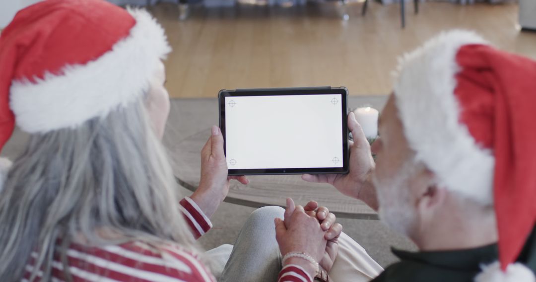 Couple in Santa Hats Using Tablet for Video Call During Christmas - Free Images, Stock Photos and Pictures on Pikwizard.com