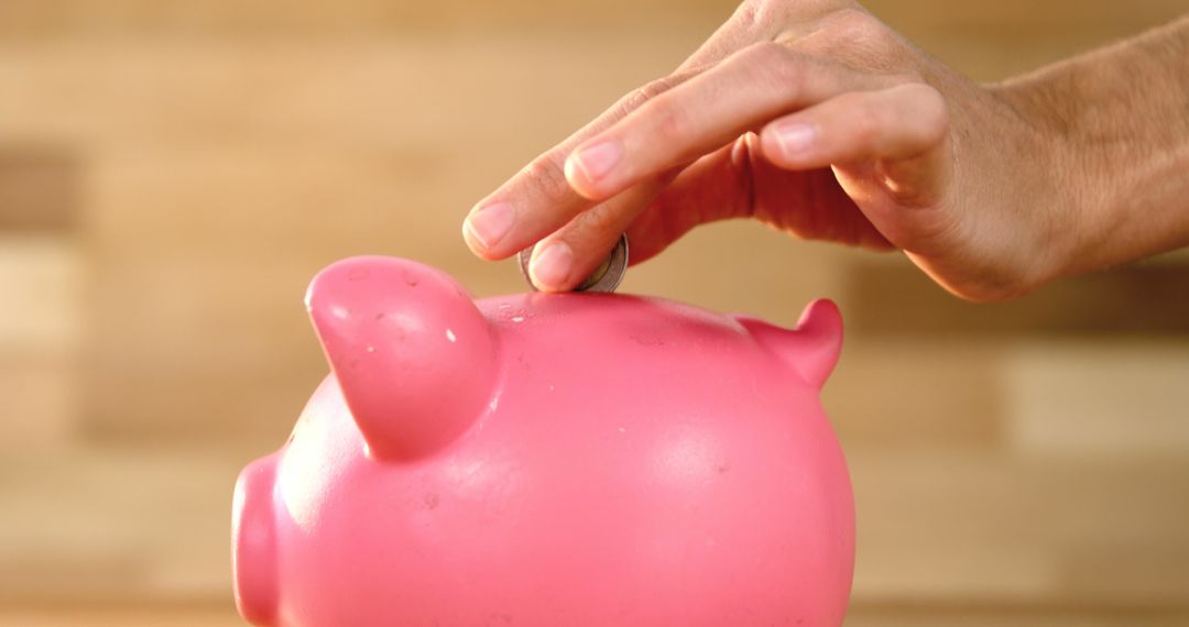 Hand placing coin in pink piggy bank for savings - Free Images, Stock Photos and Pictures on Pikwizard.com