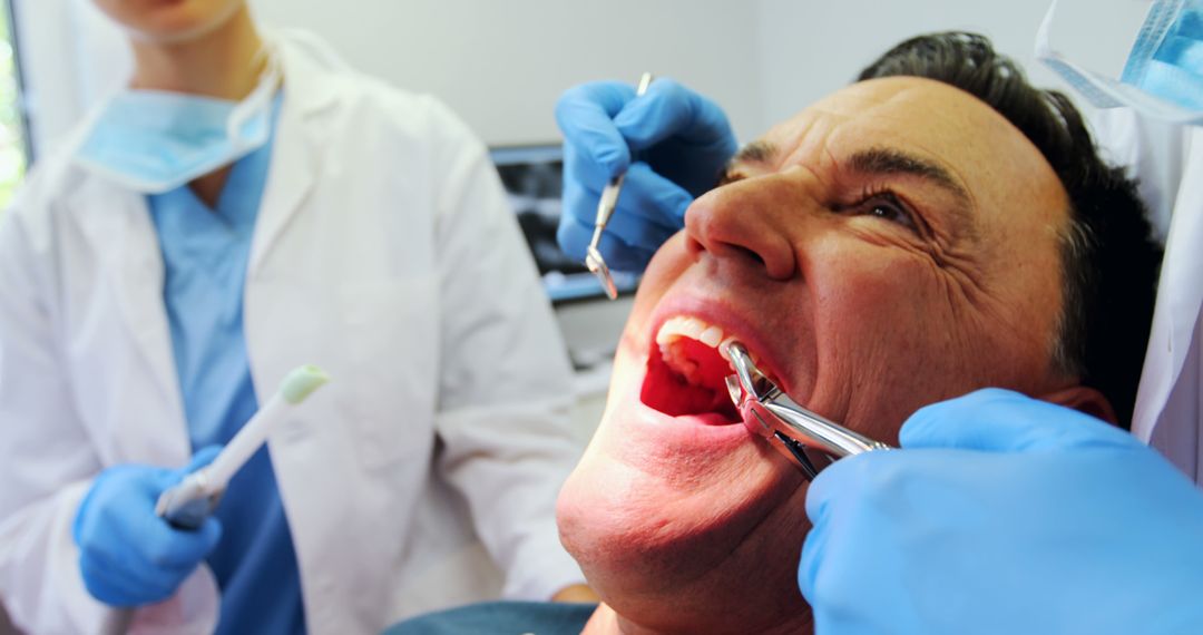 Dentist Treating Male Patient with Dental Tools in Clinic - Free Images, Stock Photos and Pictures on Pikwizard.com