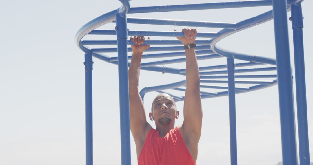 Focused Man Exercising on Blue Monkey Bars in Open Sky - Free Images, Stock Photos and Pictures on Pikwizard.com