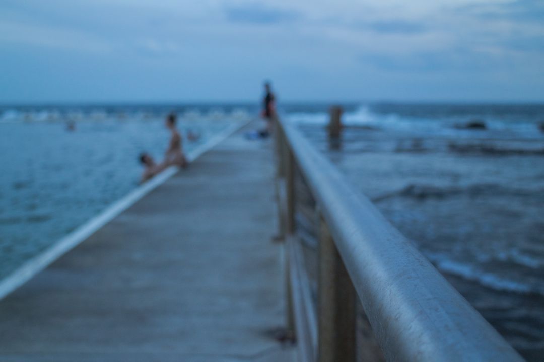 Out-of-Focus Seaside Pier with People Enjoying Ocean View - Free Images, Stock Photos and Pictures on Pikwizard.com