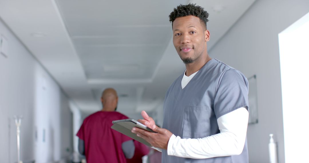 Male Nurse Using Tablet in Hospital Corridor - Free Images, Stock Photos and Pictures on Pikwizard.com