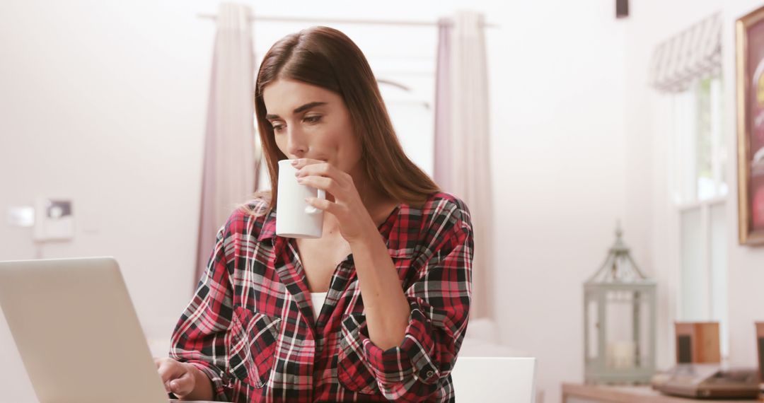 Woman Drinking Coffee While Working on Laptop in Cozy Home - Free Images, Stock Photos and Pictures on Pikwizard.com