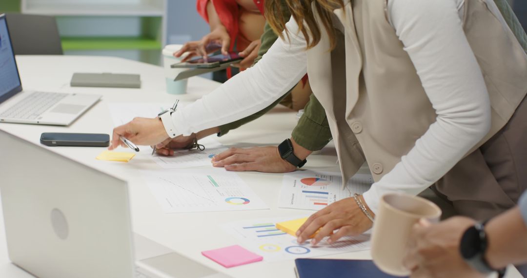 Coworkers Collaborating Over Charts, Reviewing Data, Placing Sticky Notes In Office Meeting