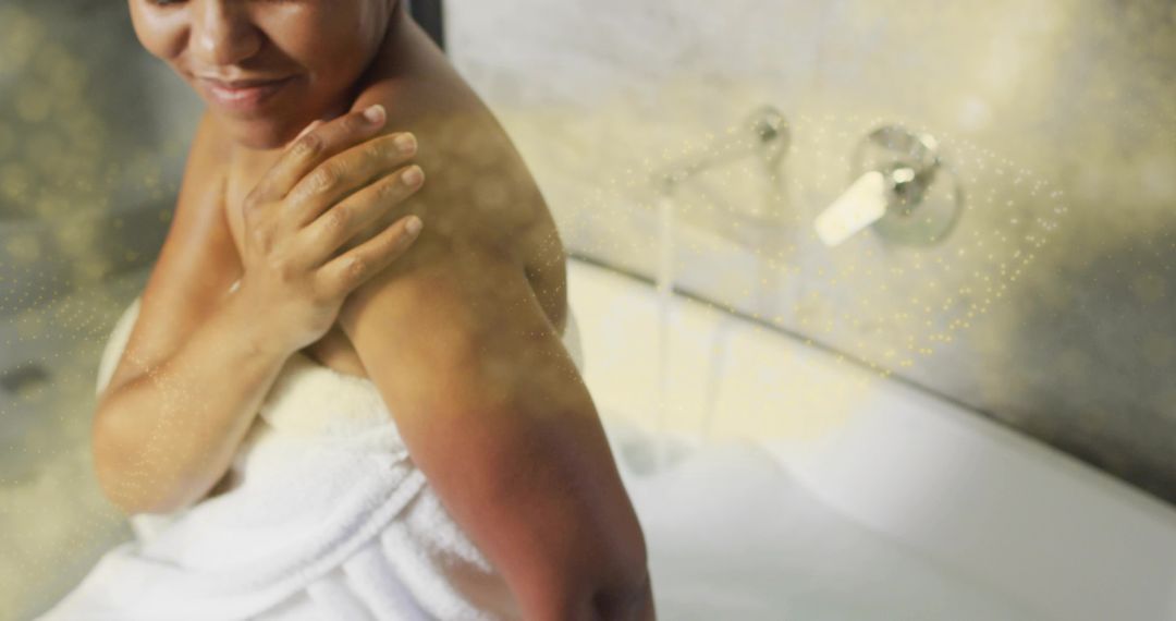 Woman wrapping towel in spa bathtub with foam and chrome faucet enjoying self-care moment