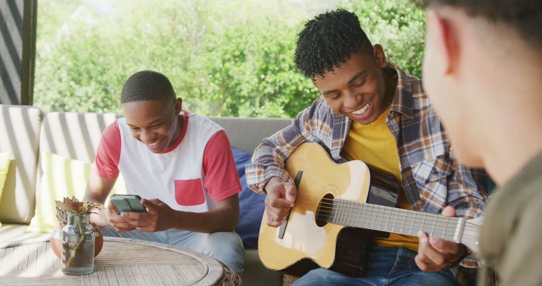 Teenagers Relaxing on Patio, Playing Guitar and Using Smartphone - Free Images, Stock Photos and Pictures on Pikwizard.com