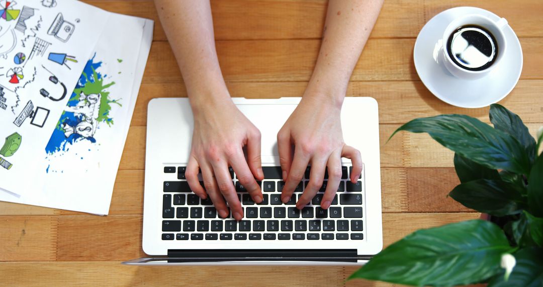 Hands Typing on Laptop Keyboard with Coffee and Plant Nearby on Wooden Surface - Free Images, Stock Photos and Pictures on Pikwizard.com