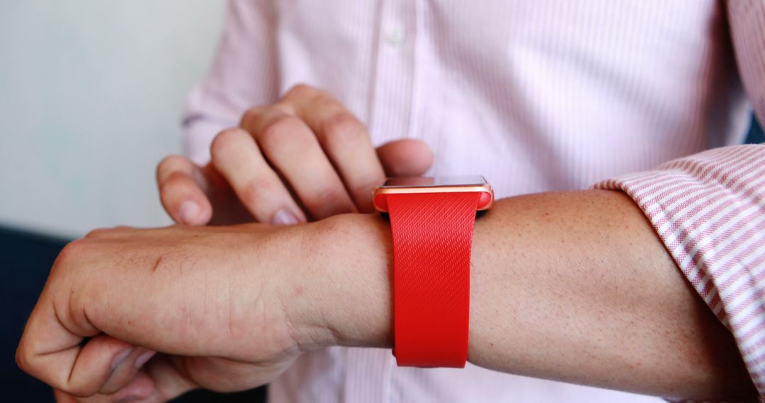 Man Adjusting Red Smartwatch Strap on Left Wrist - Free Images, Stock Photos and Pictures on Pikwizard.com