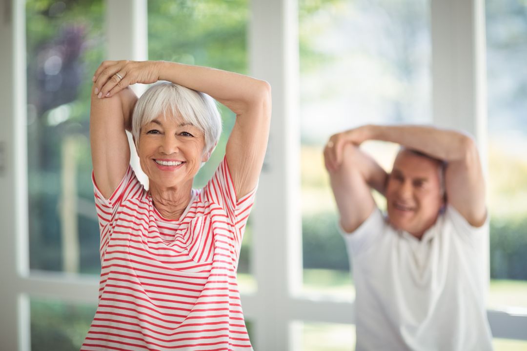 Senior Couple Smiling While Stretching Indoors - Free Images, Stock Photos and Pictures on Pikwizard.com